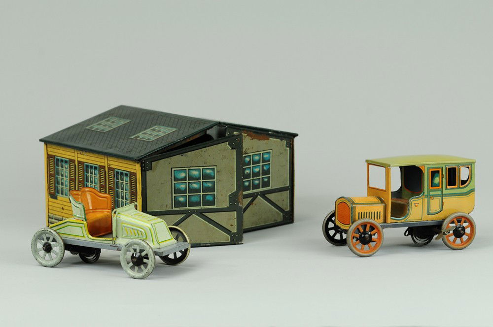 BING GARAGE WITH TWO AUTOS: Germany, lithographed tin garage w/ two opening bay doors, includes sedan model and open tourer, both clockwork driven. 8 1/2" l.