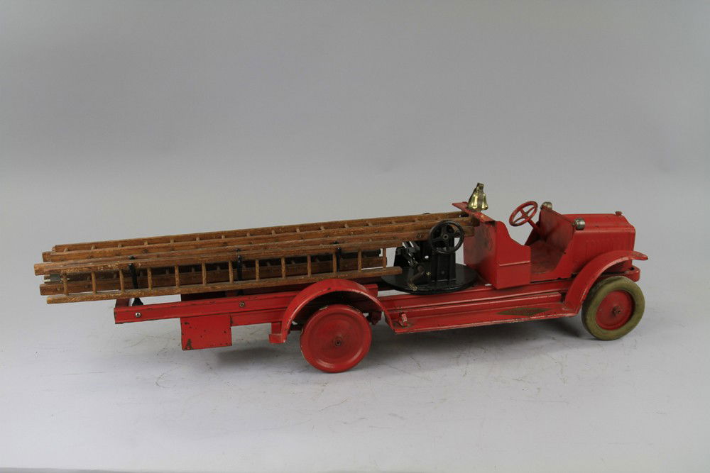 KELMET AERIAL FIRE TRUCK: C. 1920's, pressed steel, painted in red overall, "Big Boy" label appears on open cab, wooden ladders on sides, rubber tires, red disc wheels, turntable and levers on open service body. 30" l.