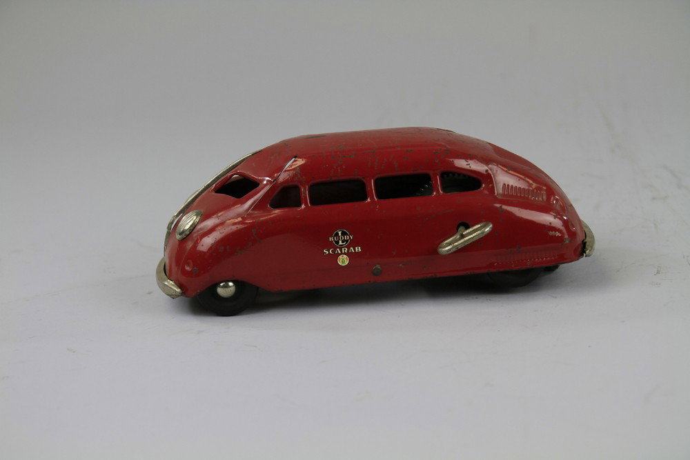 BUDDY 'L' SCARAB: C. 1936, pressed steel, painted in red overall, streamlined design, clockwork mechanism, nickel dummy lights, decals on sides, good working order. 10 1/2" l.