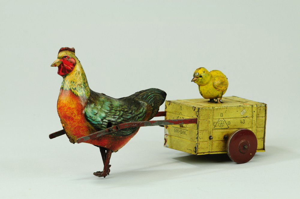 GIK-GAK HEN PULLING CHICK: Eberl, Germany, litho tin, brightly colored rooster pulls chick on simulated wood crate, EBO logo stamped on all four sides, chick squeaks when rolling, key wind mechanism. 9" l.