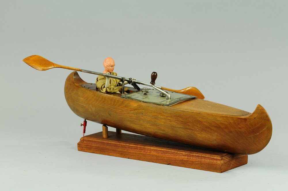 FRENCH CLOCKWORK ROWER IN CANOE: France, Auto-Rameur, made of wood and shaped into a canoe, a very early example, features celluloid head rower with long wood oars, mechanical winding action allows rowing motions, well detailed overa