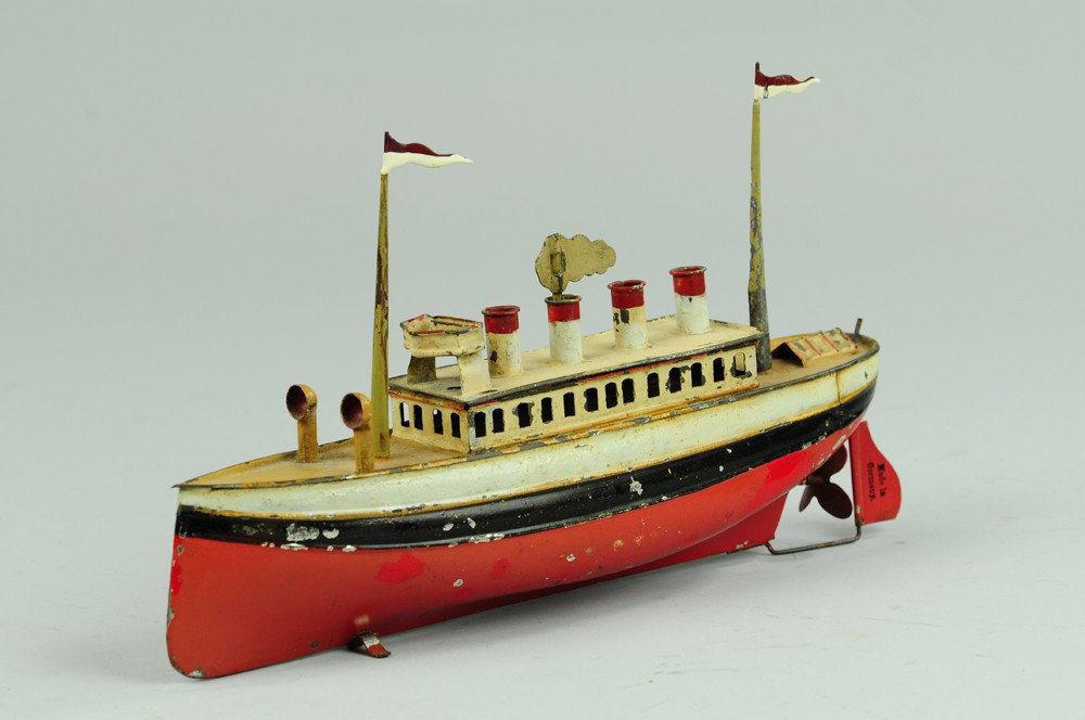 CARETTE PASSENGER BOAT: C. 1911, hand painted tin, red and black hull, white upper deck cabin, four funnels, two masts, clockwork driven. 11 1/2" l.