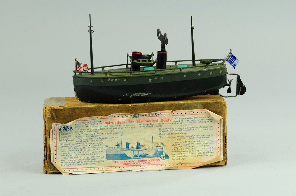 IVES BOXED DESTROYER NO. 3009: Tin ship painted in olive green with deep olive hull, clockwork driven, two masts, single stack, American flags are replacements, dislodged box has tape repairs, paper label, minor paint flaking. 9" l