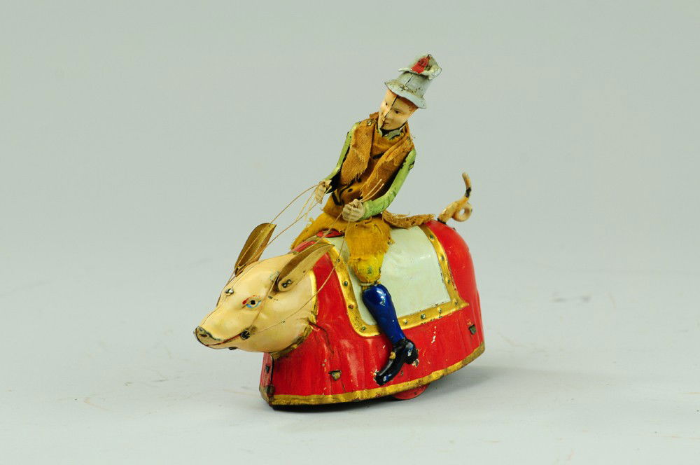 LEHMANN PADDY AND THE PIG: Germany, hand painted tin, an amusing and whimsical depiction of an Irishman riding a pig w/blanket saddle, figure wears cloth outfit, clockwork driven, a classic Lehmann toy. 5 5/8" l.