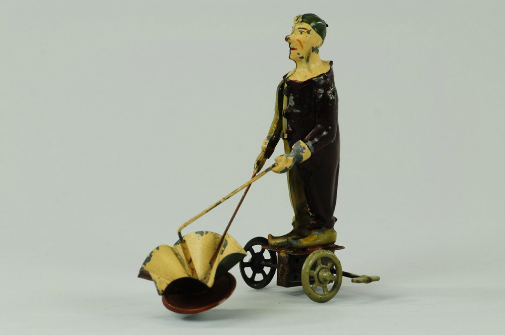 PERFORMING CLOWN CLOCKWORK TOY: Germany, hand painted tin figure of clown able to stand forward while umbrella spins and raises stick in hand. 7" h.