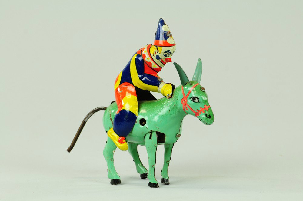 CLOWN ON DONKEY TOY: Attributed to Einfelt, Germany, lithographed tin, comical depiction of clown riding donkey, key wind driven, very colorful example. 7" h x 7" w.