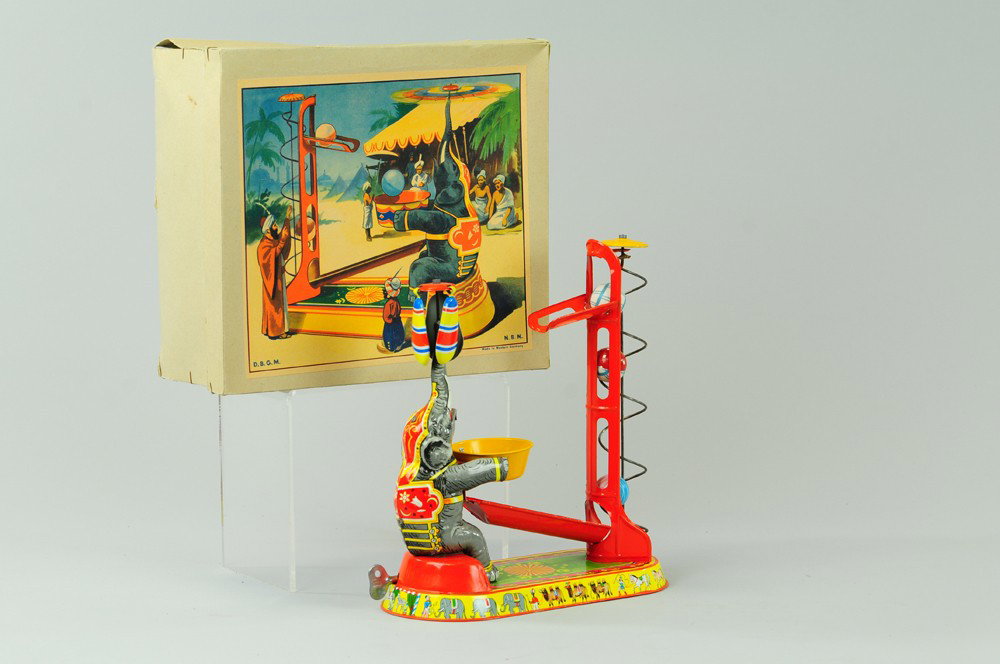 ELEPHANT BALL TOY WITH BOX: U.S. Zone, Germany, lithographed tin, clockwork, seated elephant with whirly gig and two celluloid balls. 9 1/2" h.