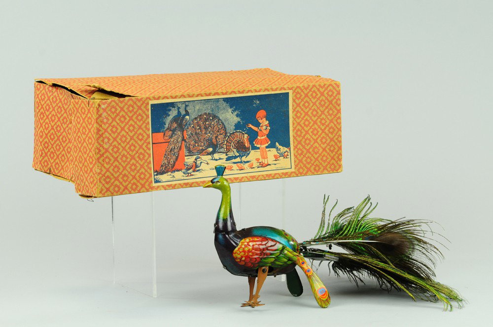 CLOCKWORK PEACOCK TOY: Germany, FMC, boxed example, features natural peacock feathers as tail, lithographed tin body, very colorful and amusing example. 10 1/2" l.