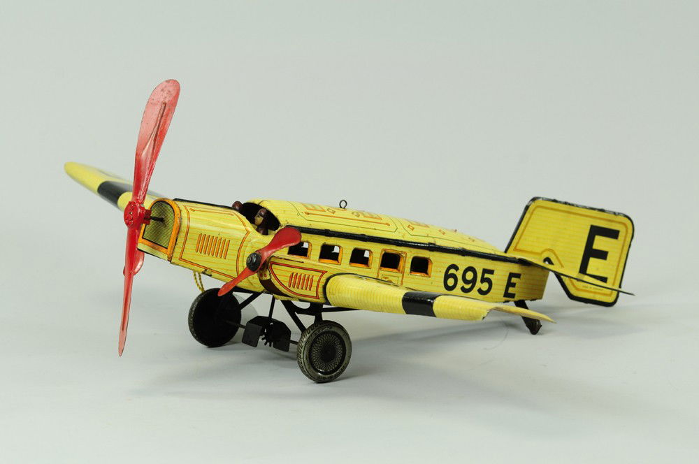 TRI-ENGINE AIRPLANE: Germany, Gunthermann, c. 1933, lithographed tin, done in yellow and black, red tri-props, wings read "695 E," good detail to images on fuselage, seated pilot and co-pilot, clockwork driven. 22" wing.