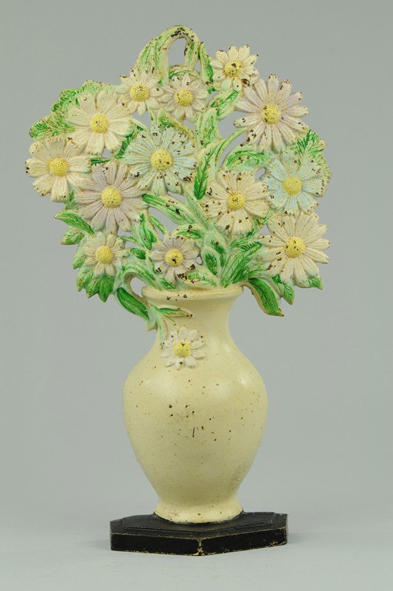 COSMOS IN VASE DOORSTOP: Hubley #455, depicts lovely large arrangement of cosmos in a white vase with black base. 17 3/4" h x 10 1/4" w.