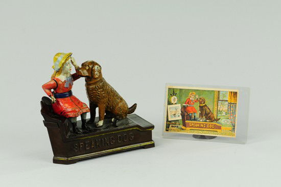 SPEAKING DOG MECHANICAL BANK WITH TRADE CARD: Red Dress, Shepard Hardware Co., designed by Charles Shepard & Peter Adams, patented 10/20/1885. The coin is placed in a plate held by the girl. The thumb-piece is pressed upon, when the girl's arm mo