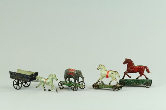 GROUPING OF SMALL TIN PULL TOYS: Early American tin toy lot includes horses, elephant and horse pulling open farm cart, all in varied colors, three on wheeled platform. 4 1/4" - 8" l.