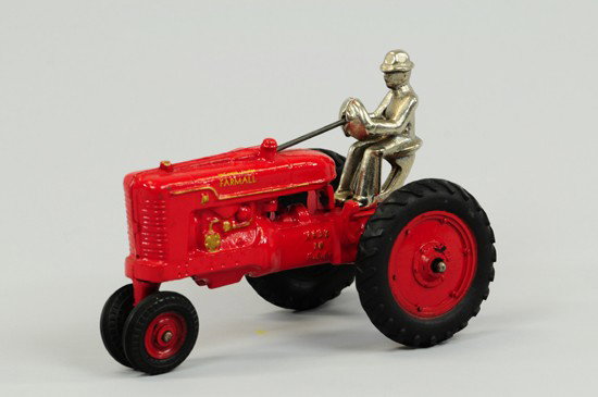 FARMALL TRACTOR: Arcade, cast iron, painted in red overall, McCormick Deering Farmall decals on both sides and Arcade Toy sticker below driver, black rubber tires and nickel plated seated figure. 7" l.