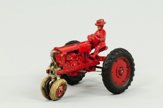 McCORMICK DEERING TRACTOR: Arcade, red painted cast iron Farmall tractor with driver cast on and black rubber tires. 6" l.