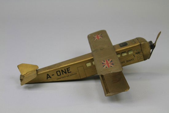 "PRIDE OF LONDON" AIRPLANE BISCUIT TIN: W. Crawford & Sons, Scotland/England, c. 1920. Lithographed tinplate finished in gold with a pair of Union Jacks on single wing, graphic windows to the sides and similar cockpit, propeller attached to