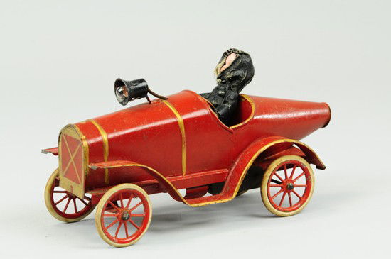 PINARD BOAT TAIL RACER: France, tin plate body painted in red with gold trim, seated bisque head driver, electric head lamp on bonnet, spoke wheels, rubber tires, clockwork driven. 11" l.