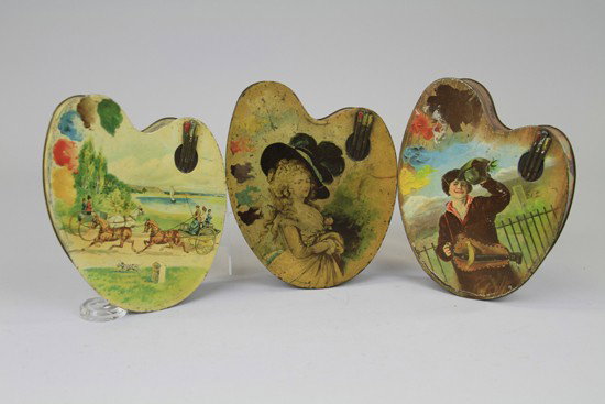 THREE HUNTLEY & PALMERS PALETTE FORM BISCUIT TINS: England, c.1902. All lithographed tinplate, each feature splotches of paint to the left and three brushes to the upper right of hinged lid. Comprising "Artist" depicting a young boy with a hurdy-gurdy