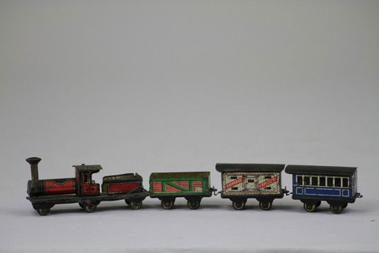 TRAIN SET PENNY TOY: Japanese, Hess style penny toy in lithographed tin, includes red and black locomotive, white and blue box cars, and green gondola. 2 1/8" to 4 1/8" l.