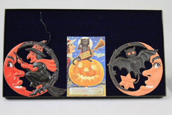 TWO LUHR HALLOWEEN DECORATIONS AND POSTCARD: Includes two German pressed cardboard Halloween decorations featuring a witch and bat 'over the moon' and black cat in pumpkin, together with Halloween postcard, all with bright strong colors. 4 1/2" 