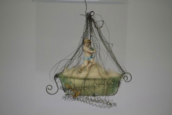 SEBNITZ BOAT ORNAMENT: Germany, Sebnitz sail boat with scrap child, wire wrap base and sail. 3 1/2" h.