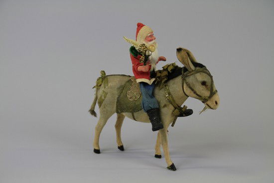 LARGE DONKEY WITH SANTA CANDY CONTAINER: Large donkey with green ribbon tack and green Dresden harness on head, large donkey ears with a black mane and large black eyes, Santa carries pipe stem tree with glass ornaments, dressed in blue with