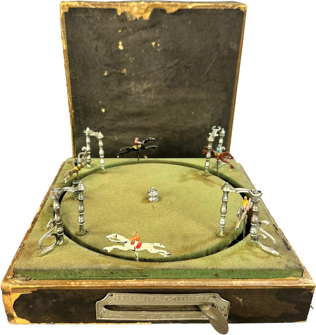 FRENCH M.J & CIE HORSE RACE GAME: 169. FRENCH M.J & CIE HORSE RACE GAME | Germany. Hand plunger causes figures to revolve around the circle simulating a race. | 10" w. base | Missing flag, typical wear to box especially around edges f
