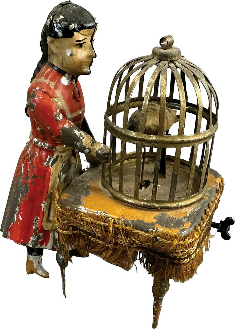 HANS EBERL GIRL FEEDING PARROT CAGE: 238. HANS EBERL GIRL FEEDING PARROT CAGE | Whimsical wind-up toy design depicts a child gesturing her right arm to feed a pecking parrot in cage, as she does a bellows squeaks from under the tabletop.