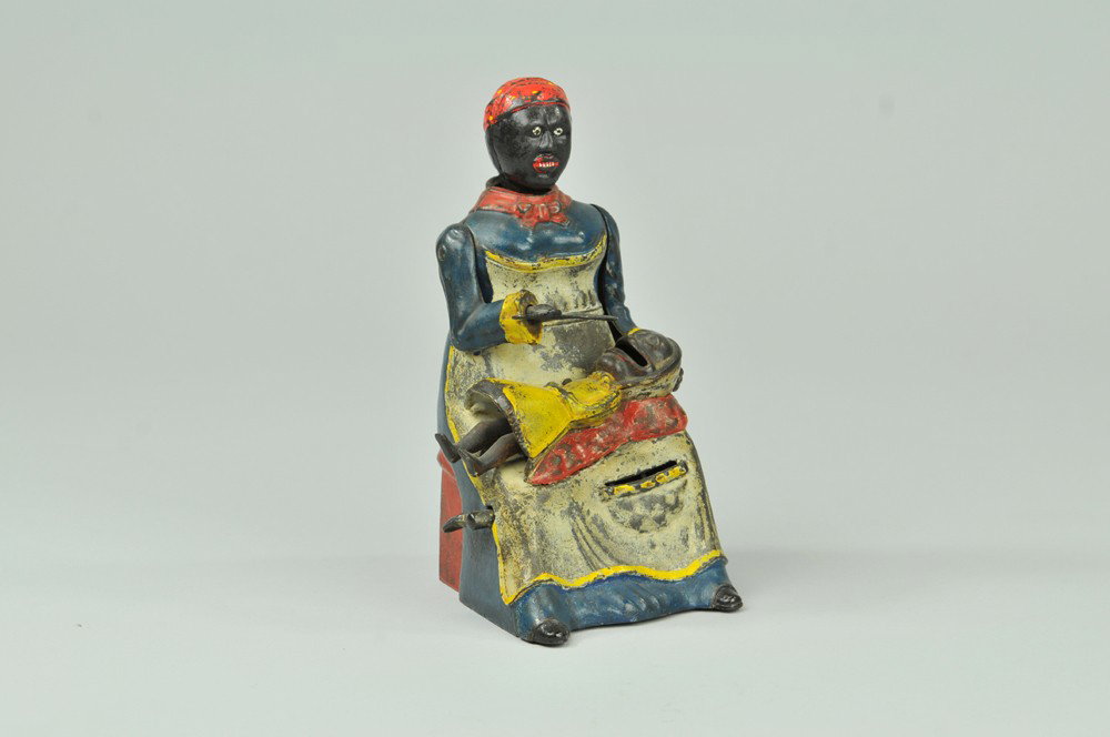 MAMMY WITH SPOON MECHANICAL BANK: Kyser & Rex Co., designed by Alfred C. Rex, patented 10/21/1884. Place a coin in the slot on the mammy’s apron and press the lever, the mammy lowers the spoon as if feeding the baby, her head lowers