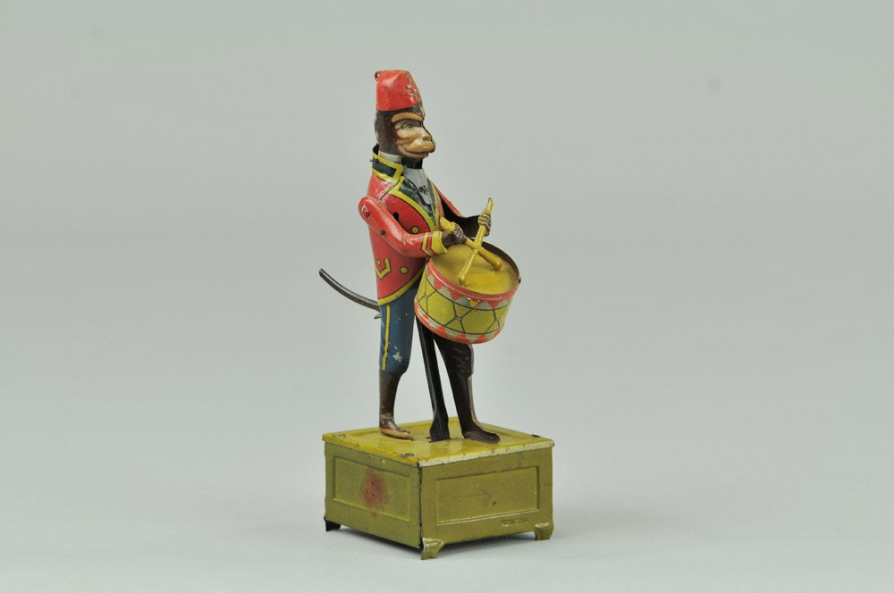 DISTLER MONKEY PLAYING DRUM: Germany, lithographed tin, depicts suited monkey standing on base while playing parade drum when clockwork is activated. 8" h. (VG - Exc. Cond.) 8" h.