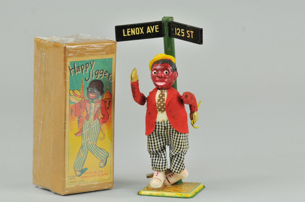 BOXED HAPPY JIGGER TOY: Alps, Japan, celluloid head, cloth body, stands on litho tin base and street sign marked "Lennox 125 St.," key wind operated. 8 1/2" h. (Pristine Cond.) 8 1/2" h.