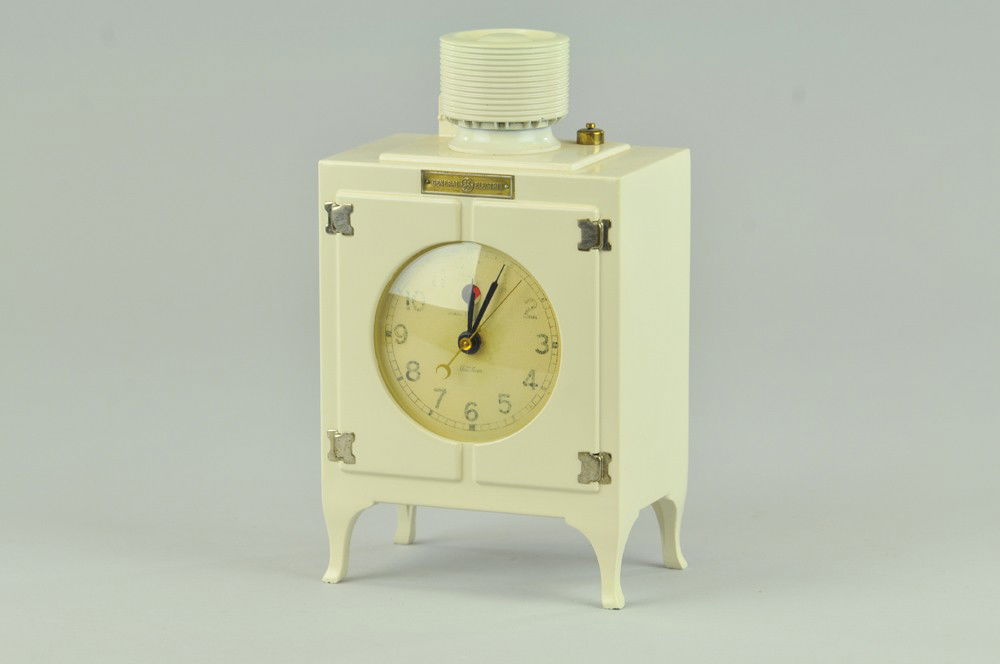 GENERAL ELECTRIC CLOCK: Made by Telechron of Massachusetts, electric clock in shape of refrigerator with clock face at center of front panel. 8" x 5" x 3" Missing cord, clock paper faded, repainted. 8" x 5" x 3"