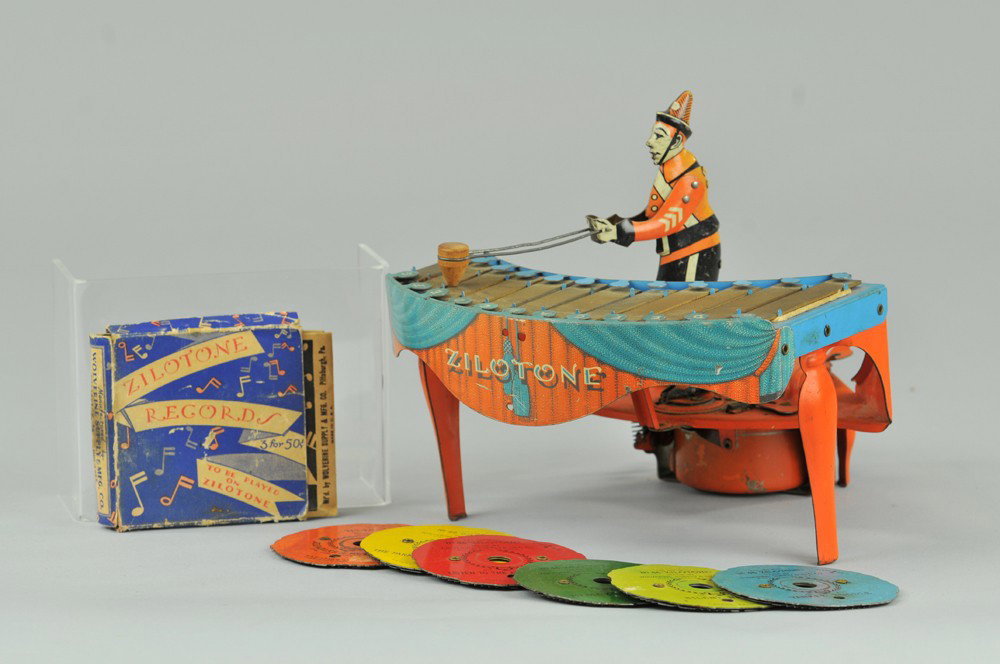 ZILOTONE: Wolverine Mfg., tin and pressed steel musical toy depicts figure at play on zilotone, colorful keyboard orange instrument clockwork mechanism activates spinning records and drumming motion by figure. 
