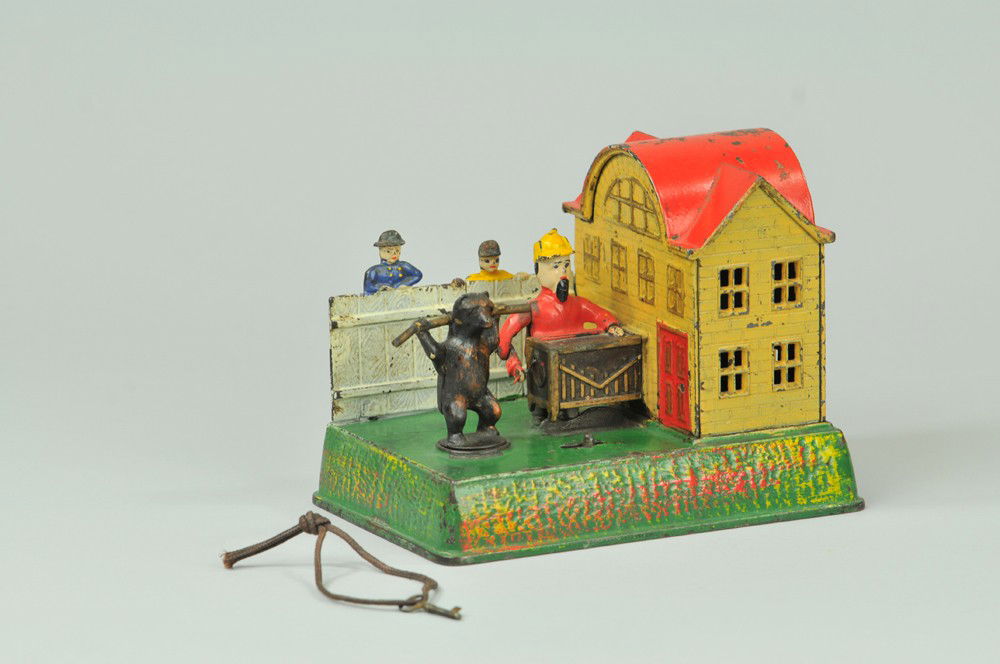 ORGAN GRINDER AND PERFORMING BEAR MECHANICAL BANK: Kyser & Rex Co., circa 1890's. This bank represents the front of a country house with an Italian organ-grinder and a bear on the lawn. After winding up the mechanism, place a coin in the slot and push