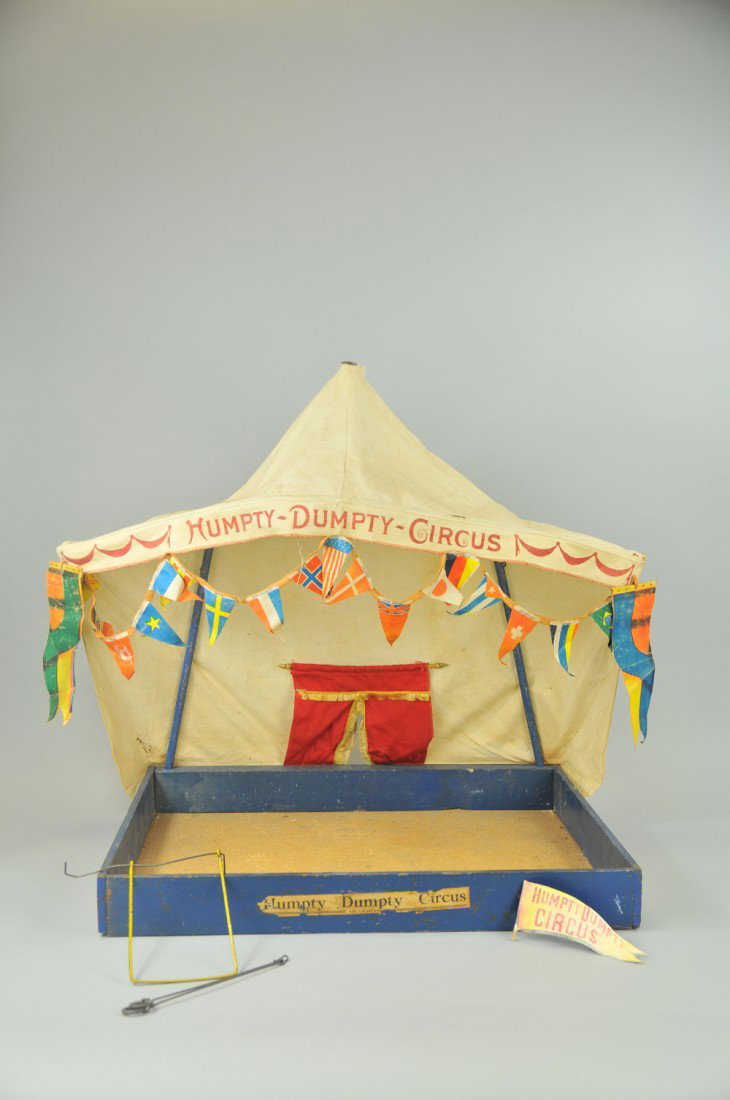 SCHOENHUT REDUCED SIZE TENT: Canvas top with multi-flags as streamers, interior red entrance curtain, contains wire trapeze bar, a very realistic miniature scale circus settings. 23" x 21". Wear to wood bob ring, some tears to te