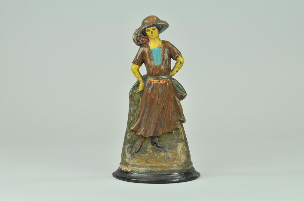 FLAPPER GIRL DOORSTOP: BOOK EXAMPLE, Marked "E.O.M. Co., Toledo, O., 2.," cast iron, well molded casting depicts young woman in brown flowing dress w/beautiful flower detailing, rare & very desirable. 12" x 6 1/2". (Pristin