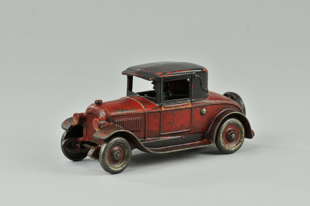 KENTON COUPE: c. 1920's, a desirable toy coupe done in red body, black roof and running boards silver spare typical crazing to paint. 8 1/4" l. (VG - Exc. Cond.) 8 1/4" l.