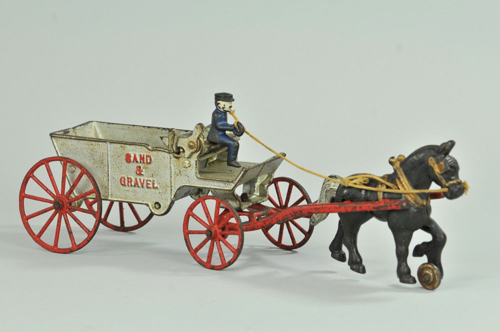 SAND AND GRAVEL WAGON: Kenton, cast iron, very scarce and elusive silver painted dump wagon, embossed on sides, red spoke wheels, seated driver, drawn by black horse. 15" l. (VG Cond.) 15" l.