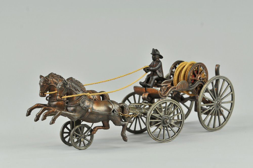 KENTON HORSE DRAWN HOSE REEL: An early electroplated hose reel toy, drawn by two horses, small barrel reel rest on ornate open frame, spoke wheels. 14" l. Crack at hose reel support and repair, overall (VG Cond.) 14" l.