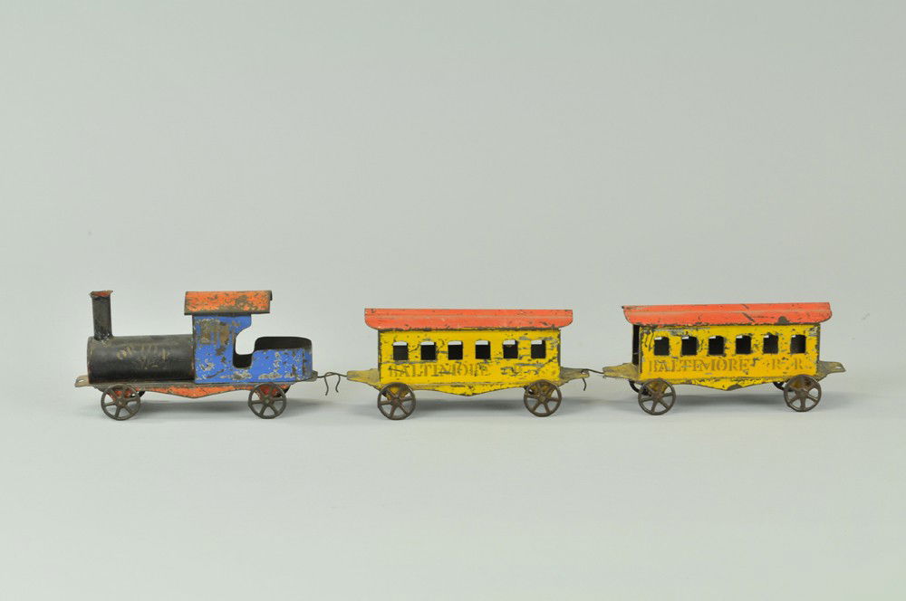 ORION FLOOR TRAIN: Early American tin, loco marked Orion, two coaches stenciled "Baltimore" hand-painted circa late 1880's. 5 1/2" l. Paint wear, overall (VG Cond) 5 1/2" l.