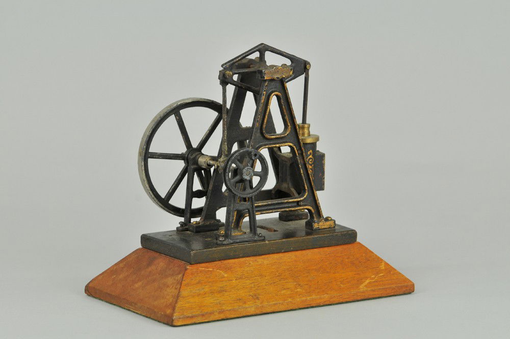 WALKING BEAM OSCILLATING CYLINDER ACCESSORY: Cast iron supports, painted in black, pulley ready to attach to steam engine, mounted on home made wood base, brass cylinder. 5" x 5 1/2". (VG Cond) 5" x 5 1/2".