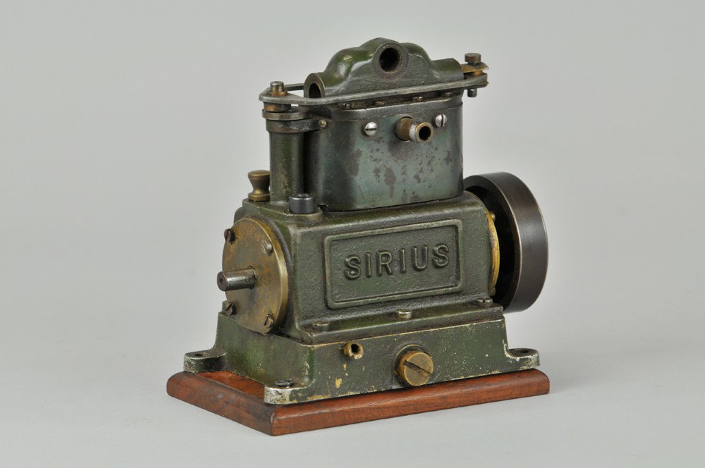 STUART SIRIUS STEAM ENGINE: Live steam twin cylinder engine, heavily cast in iron, embossed lettering on both sides, missing some apparatus appointments, spins freely. 6 1/2" l. (Good Cond) 6 1/2" l.