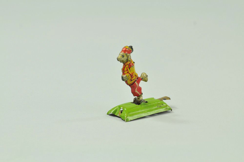 STANDING DOG PENNY TOY: Meier, Germany, amusing theme, lithographed tin figure of suited dog with articulated action, green platform. 1 3/4" l. (Exc. Cond.) 1 3/4" l.