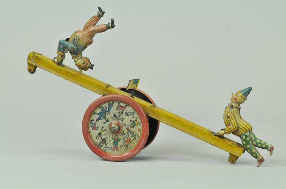 DISTLER CLOWNS ON SEE-SAW TOY: Germany, lithographed tin, amusing example depicts performing circus clowns on each end of see-saw with large wheels at center, good graphic images overall, small flag on pole, pictures gorilla on eac