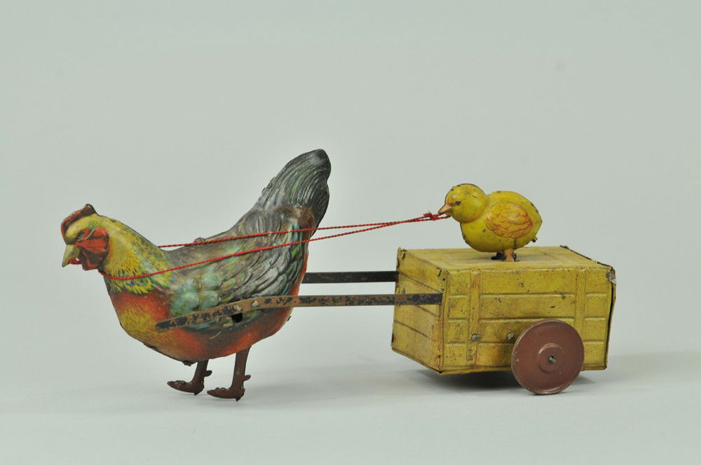 HANS EBERL HEN AND CHICK CART: Germany, lithographed tin, depicts large hen pulling simulated tin wooden crate with small chick at top which pecks as it is pulled along, clockwork appears over wound. 9 1/2" l. Denting to cart. (VG