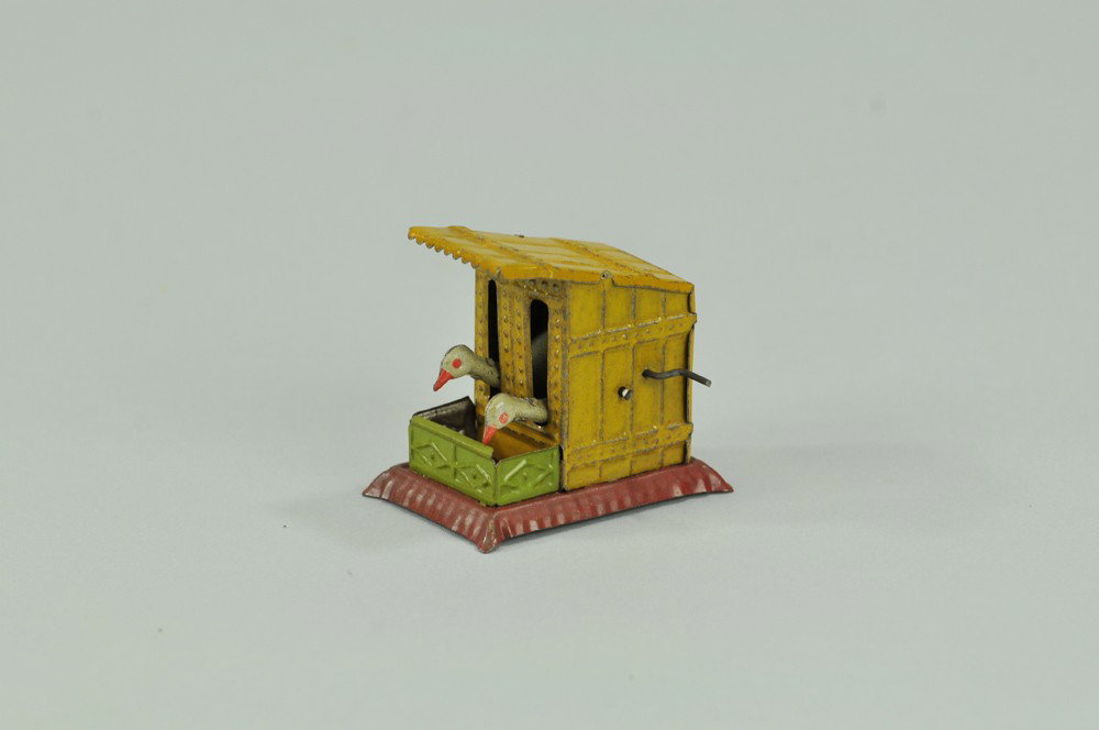 PECKING GEESE PENNY TOY: Meier, Germany, lithographed tin, depicts coop and two geese with protruding heads able to peck at trough when lever is turned. 2" x 2 1/4" l. (Exc. Cond) 2" x 2 1/4" l.