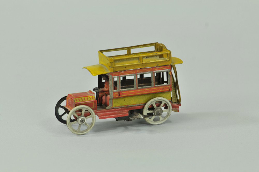 DISTLER BUS PENNY TOY: Germany, lithographed tin, done in red and yellow, stairs lead to railed upper deck, seated driver, key wind driven, bending to railing. 4 1/2" l. (VG Cond) 4 1/2" l.