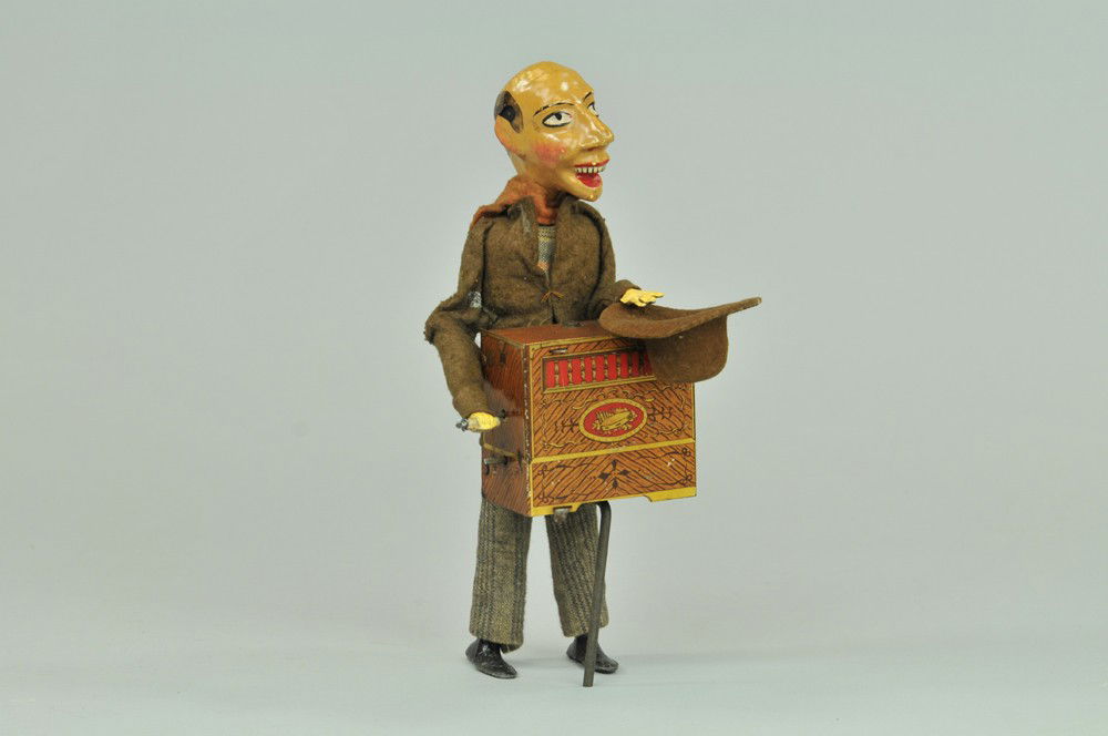 VICTOR BONNET STREET MUSICIAN: France, hand-painted head, appears as some suggest as a grotesque street performer, wears felt suit, clockwork activated litho tin, organ on pole stand, very whimsical overall, a very nice example. 9"