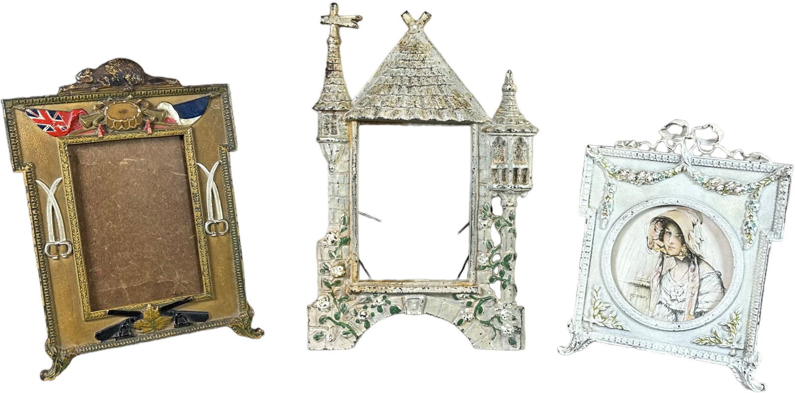 THREE FIGURAL CAST IRON DECORATIVE PICTURE FRAMES: 1184. THREE FIGURAL CAST IRON DECORATIVE PICTURE FRAMES | Includes Castle, cjo flowers with bow and cjo military theme frames. | 10.5" h. | (Excellent to Pristine Condition) | $150 - $300