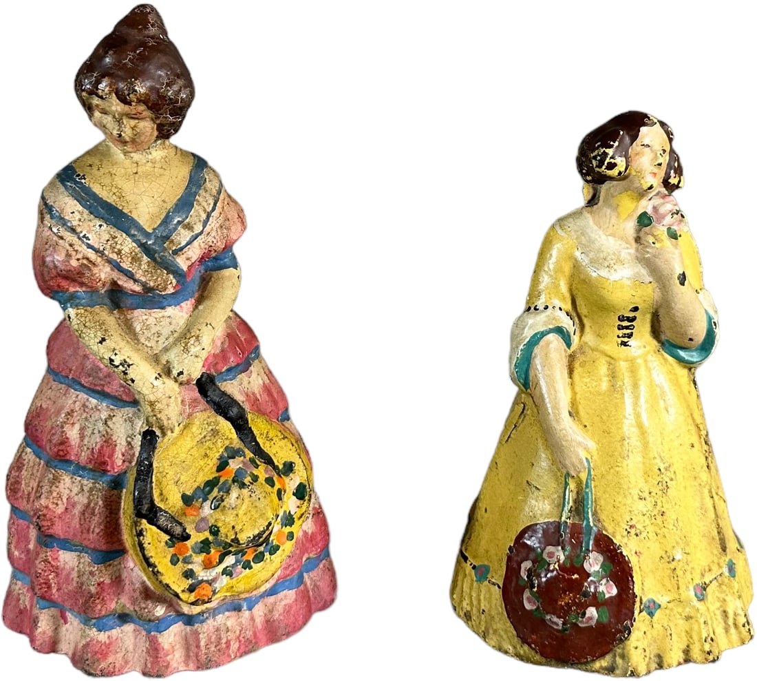 TWO WOMAN HOLDING HATS DOORSTOPS: 1288. TWO WOMAN HOLDING HATS DOORSTOPS | One full figure-solid, one hollow body. | 7.5" h. | (Excellent to Pristine Condition) | $150 - $300