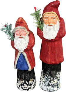 TWO RED COAT BELSNICKLES: 98. TWO RED COAT BELSNICKLES | Open coat with blue robe is harder to find, large one has a fuzzy coat. | 9.5"-11.5" h. | Smaller piece missing cardboard base at underside, larger Santa has two tiny to
